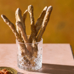 Sprøde fuldkornsgrissini med sesam serveret som snack i et glas.