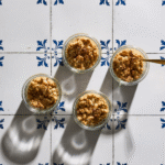 Lun pærecrumble med sprød topping af mandler og havregryn anrettet i fire glas.