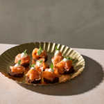 Små rugbrødsblinis med koldrøget laks, citroncreme og frisk dild.